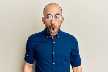 Gündelik giysiler ve gözlük takan genç İspanyol bir adam. Şaşırtmak için ağzı açık, korkmuş ve şaşırmış. İnanmayan yüz. 