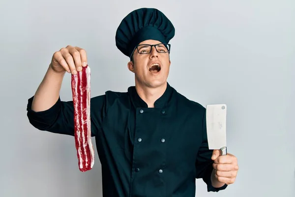 Handsome Young Man Wearing Chef Uniform Holding Bacon Knife Angry — Stock Photo, Image