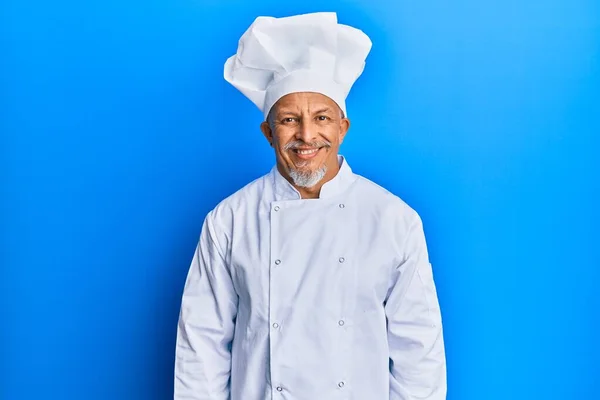 プロの料理人の制服を着た中年の白髪の男と顔に幸せとクールな笑顔で帽子 運のいい人 — ストック写真