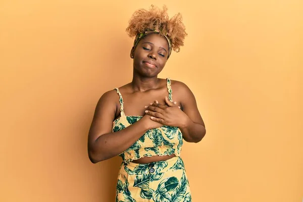 目を閉じて胸に手で笑みを浮かべて夏のドレスを着てアフロの髪を持つ若いアフリカの女性と顔に感謝のジェスチャー 健康の概念 — ストック写真