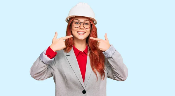 Jonge Roodharige Vrouw Met Een Architectenhelm Die Vrolijk Glimlacht Wijst — Stockfoto