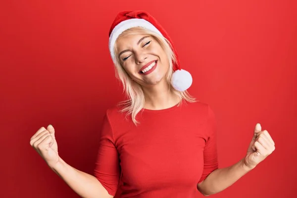 Молодая Блондинка Рождественской Шляпе Счастлива Взволнована Делая Жест Победителя Поднятыми — стоковое фото