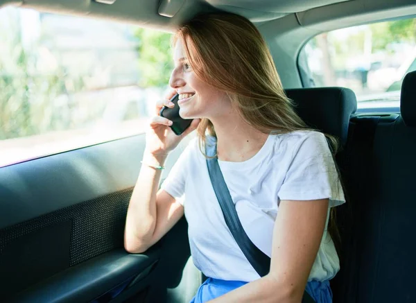Genç, güzel, sarışın, gülümseyen, mutlu bir kadın. Arabada oturmuş, akıllı telefondan konuşuyor..
