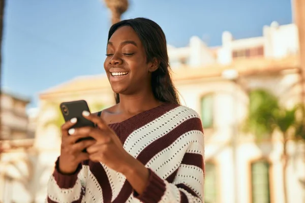 Νεαρή Αφροαμερικανή Γυναίκα Χαμογελά Ευτυχισμένη Χρησιμοποιώντας Smartphone Στην Πόλη — Φωτογραφία Αρχείου