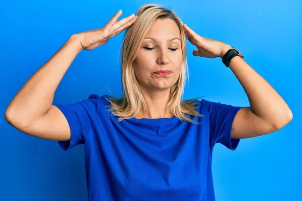 中世の白人女性が頭の上に手でカジュアルな青のTシャツを着て 頭痛の種ので ストレス 片頭痛 — ストック写真