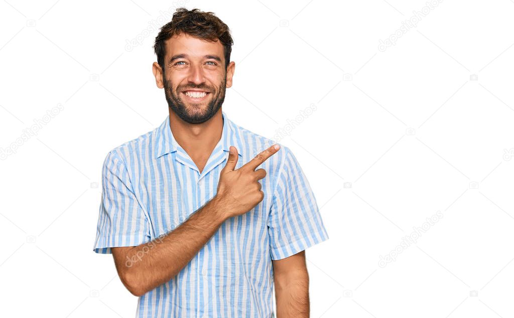 Handsome young man with beard wearing casual fresh shirt cheerful with a smile of face pointing with hand and finger up to the side with happy and natural expression on face 