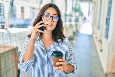 Ciddi bir suratı olan genç İspanyol iş kadını şehirdeki akıllı telefondan konuşuyor..