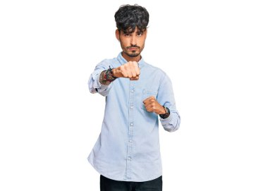 Latin kökenli genç adam gündelik kıyafetler giyiyor. Yumruk yumruğa dövüşüyor, agresif ve öfkeli saldırı, tehdit ve şiddet uyguluyor. 