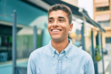 Genç Latin adam gülümseyerek şehirde mutlu mesut yürüyor..