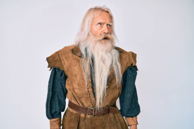 Gri saçlı, uzun sakallı, Viking kostümü giyen kızgın, kızgın ve öfkeli yaşlı bir ihtiyar. Öfkeyle bağırıyor. öfke ve agresif konsept. 