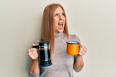 Genç İrlandalı kadın öfkeli ve öfkeli bir şekilde bağırarak İtalyan kahvesi içiyor. Öfkeyle bağırıyor. öfke ve agresif konsept. 