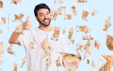 Neşeli ve pozitif gülümseyen İspanyol asıllı genç adam, mükemmel ve onay işareti yapıyor.