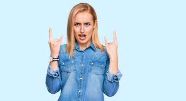 Sıradan kot ceket giyen, çılgın bir ifadeyle bağıran, elleri havada rock sembolü yapan güzel beyaz bir kadın. Müzik yıldızı. ağır kavram. 