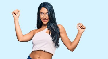 Güzel İspanyol kadın gündelik kıyafetler giyip dans ediyor mutlu ve neşeli, gülümsüyor rahat ve kendinden emin bir şekilde müzik dinliyor. 