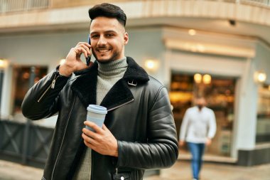 Genç Arap akıllı telefondan konuşuyor. Şehirde kahve içiyor..