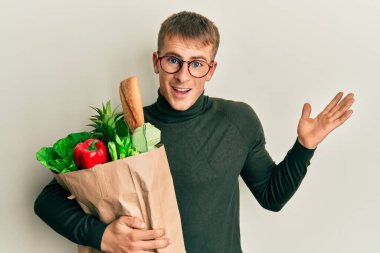 Elinde alışveriş poşeti olan beyaz bir genç zaferi mutlu bir gülümsemeyle kutluyor ve kazanan el kaldırarak ifade ediyor. 