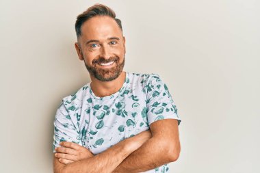 Yakışıklı, orta yaşlı, sıradan giyinen mutlu yüzlü, kollarını kavuşturup kameraya bakan bir adam. pozitif kişi. 