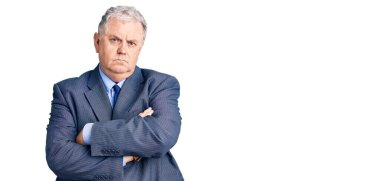 Kıdemli gri saçlı, iş ceketi giyen, kuşkucu ve gergin, yüzünde çapraz kollu tasvip etmeyen bir ifade. negatif kişi. 