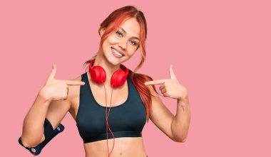 Genç kızıl saçlı, spor kıyafetleri giyen, kulaklık takan, kendine güvenen, gülümseyen, kendini gururlu ve mutlu gösteren bir kadın.. 