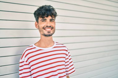 Genç İspanyol adam gülümsüyor mutlu bir şekilde şehrin duvarına yaslanıyor..