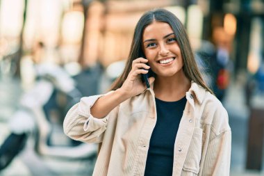 Genç İspanyol kız gülümsüyor. Şehirdeki akıllı telefondan konuşuyor..