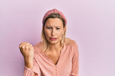 Orta yaşlı beyaz kadın, günlük kıyafetler giyiyor kızgın ve kızgın yumruk kaldırıyor öfkeyle bağırırken sinirli ve öfkeli. öfke ve agresif konsept. 