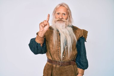 Gri saçlı, uzun sakallı, Viking kostümü giyen yaşlı bir adam başarılı bir fikirle işaret ediyor. Heyecanlı ve mutlu. Bir numara.. 