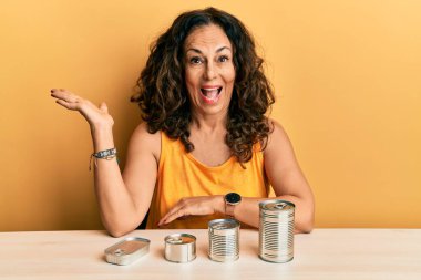 Konserve yiyeceklerle güzel bir orta yaşlı kadın zaferi mutlu bir gülümsemeyle kutluyor ve kazanan ifade ellerini kaldırarak ifade ediyor. 