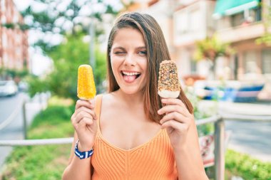 Genç ortadoğulu kız dil ısırıyor ve şehirde dondurma tutuyor..