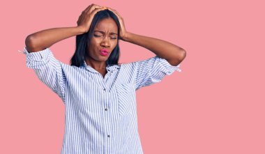 Genç Afro-Amerikalı kadın gündelik kıyafetler giyiyor. Baş ağrısı çekiyor, çaresiz ve stresli. Çünkü acı ve migren ağrısı var. Eller başının üstünde.. 