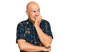 Orta yaşlı, kel, sıradan kıyafetler giyen, gergin ve elleri ağızdan tırnak yiyen bir adam. anksiyete. 