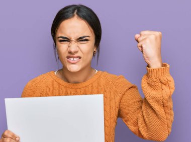 Boş pankart tutan genç esmer kadın öfkeyle bağırıyor, öfkeyle bağırıyor ve el kaldırıyor. 