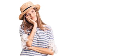 Yazlık şapka takan güzel beyaz kadın kollarını kavuşturarak depresyondan sıkılmış ve yorgun görünüyor.. 