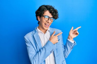 İş ceketi giyen, gözlüklü, gülümseyen ve kameraya bakan İspanyol genç bir adam.. 