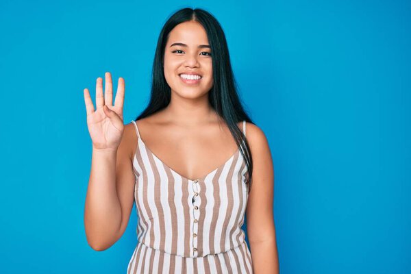 Young beautiful asian girl wearing casual clothes showing and pointing up with fingers number four while smiling confident and happy. 