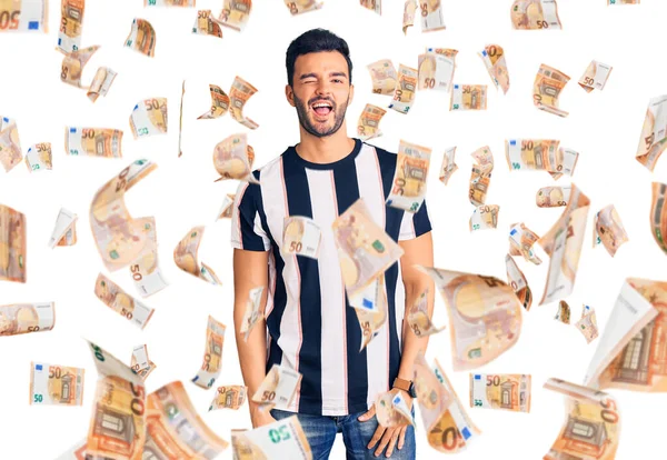 Genç, yakışıklı, çizgili tişört giyen ve kameraya seksi bir ifadeyle bakan neşeli ve mutlu yüzlü bir adam..