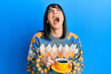 Genç İspanyol kadın bir fincan kahve içiyor kızgın ve kızgın çığlık atıyor sinirli ve öfkeli, öfkeyle bağırıyor.. 