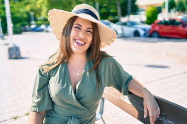 Genç İspanyol kadın tatilde gülümsüyor. Mutlu bir şekilde şehrin sokaklarında bankta oturuyor.