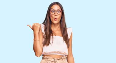 Gündelik giysiler ve gözlük takan genç İspanyol kadın parmaklarını yana çevirerek şaşırdı, ağzı açık hayret içinde kaldı.. 