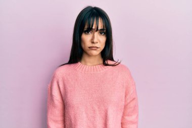 Kâküllü, kışlık süveter giyen, kuşkucu ve gergin genç esmer kadın sorun yüzünden üzgün. negatif kişi. 