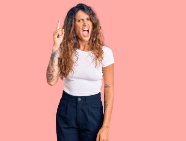 Gündelik beyaz tişört giyen Latin kökenli genç bir kadın başarılı bir fikri işaret ediyor. Heyecanlı ve mutlu. Bir numara.. 