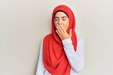 Geleneksel İslami başörtüsü takan genç, güzel İspanyol kız, ağzını eliyle kapatmaktan sıkılmış, esnemekten sıkılmış. Huzursuz ve uykulu.. 