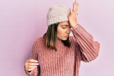 Yün süveter ve kış şapkası giyen genç, beyaz bir kadın, rahat bir görünüm ve kendine güvenen bir gülümseme takınıyor.. 