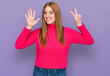 Genç İrlandalı kadın gündelik giysiler giyer ve yedi numaralı parmaklarıyla işaret ederken kendinden emin ve mutlu bir şekilde gülümserdi.. 