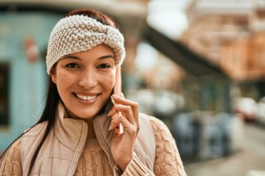 Genç Latin kadın akıllı telefonda konuşuyor. Şehirde kahve içiyor..