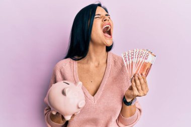 Genç, beyaz bir kadın elinde Norveç Krona banknotları ve domuz kumbarası tutuyordu. Öfkeli ve öfkeli çığlıklar atıyordu. Öfkeyle bağırıyordu.. 