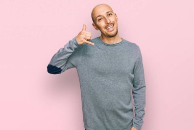 Sakallı, sıradan kıyafetler giyen, gülümseyen, el ve parmaklarıyla telefon hareketi yapan, telefonda konuşan kel bir adam. iletişim kavramları. 