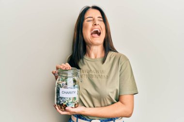 Orta yaşlı esmer kadın elinde para dolu bir kavanozla öfkeli ve kızgın çığlıklar atan öfkeli ve öfkeliydi. Öfkeyle bağırıyordu.. 