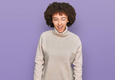 Yün kazak giyen genç İspanyol kız kameraya seksi bir ifadeyle bakıyor, neşeli ve mutlu bir yüzle.. 