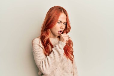 Genç, güzel, kızıl saçlı, sıradan bir kazak giyen, kendini kötü hisseden ve soğuk algınlığı veya bronşitin belirtisi olarak öksüren bir kadın. sağlık hizmeti kavramı. 